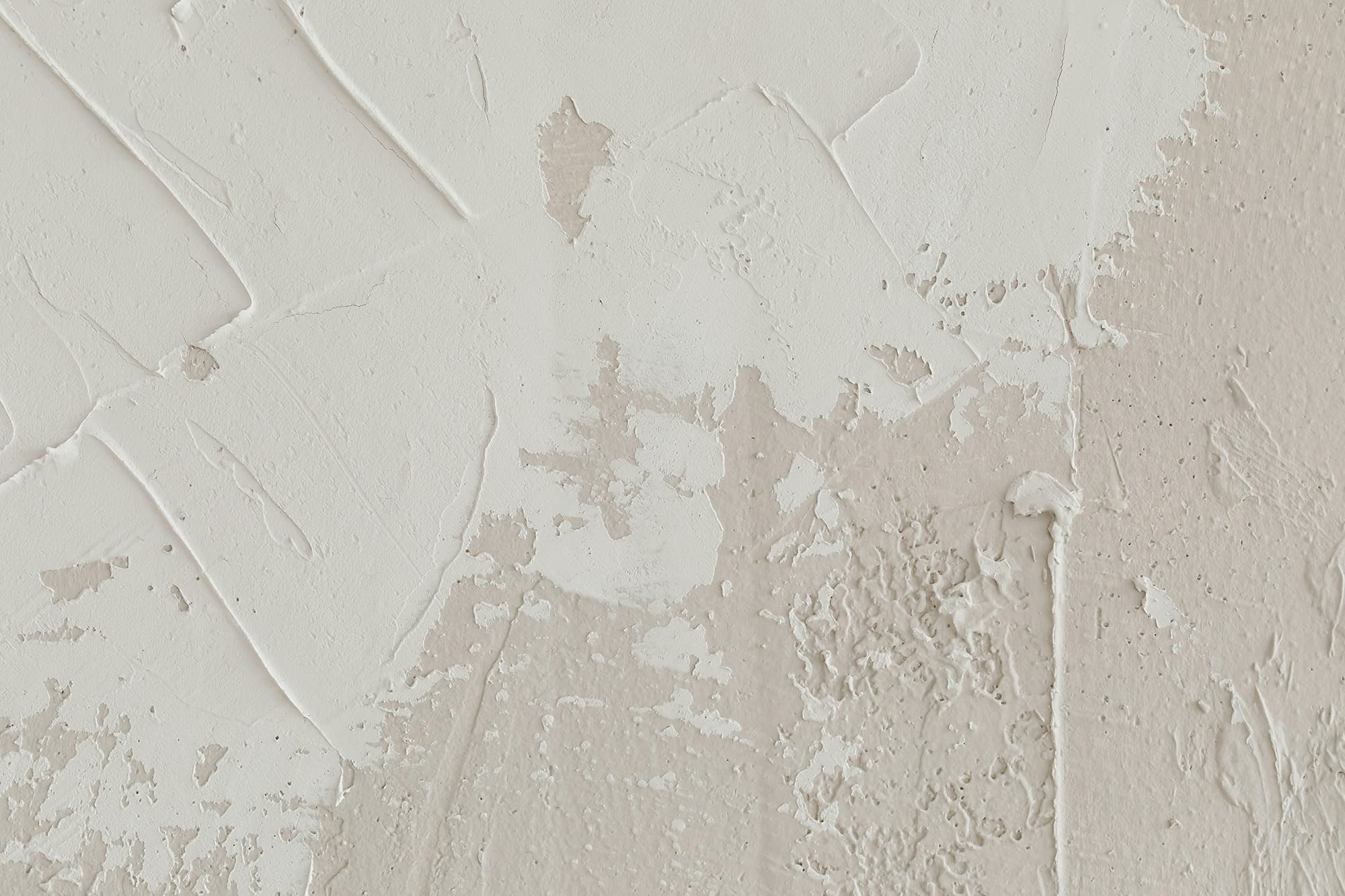 A white textured wall accented with beige paint strokes.